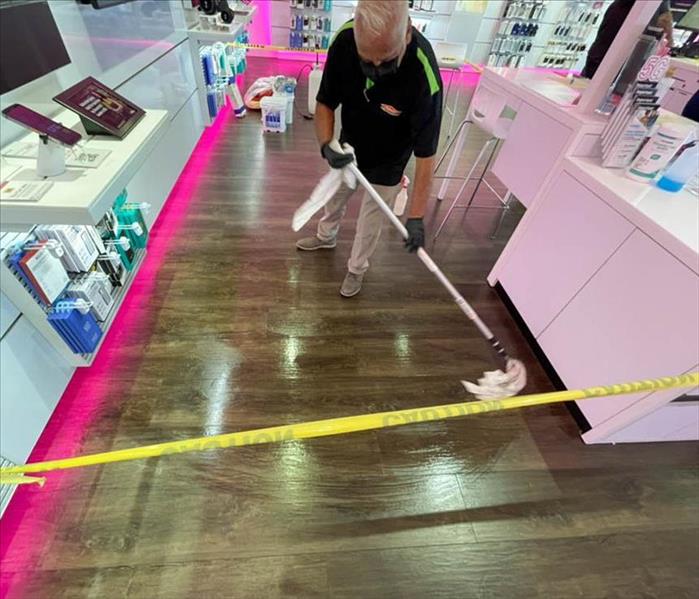 Employee cleaning floor of store. 